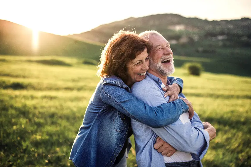 Couple senior souriant et se tenant dans les bras, symbolisant le bien-être et la sérénité offerts par une mutuelle santé adaptée.