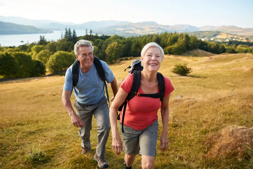 Un couple de seniors en pleine randonnée en montagne, incarnant la liberté et l’autonomie grâce à la prévoyance.