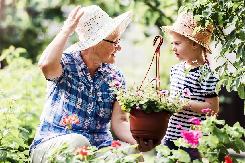 Une grand-mère et sa petite-fille jardinant ensemble et échangeant, un moment de complicité et de transmission.