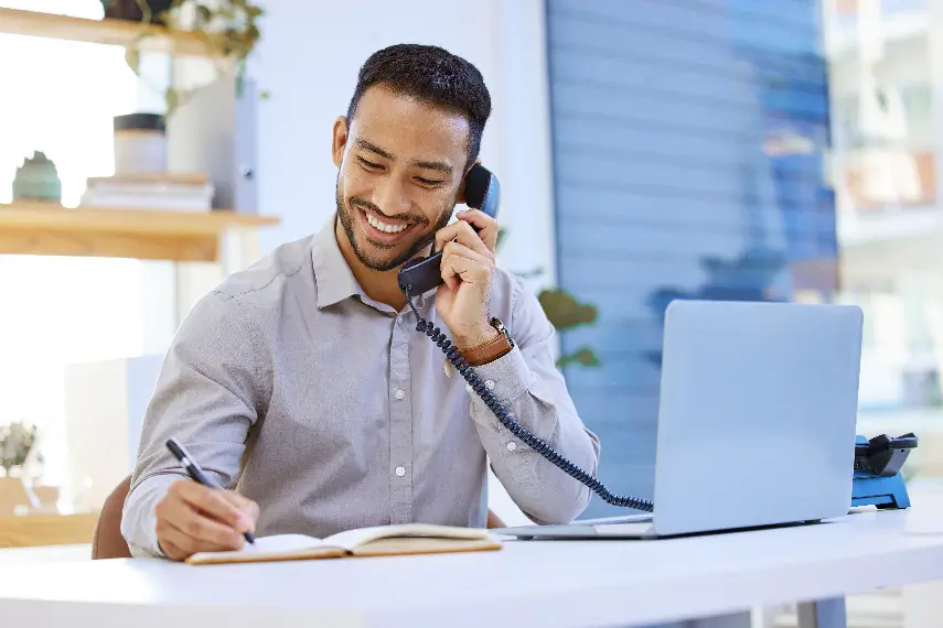 Un agent souriant au téléphone, prêt à répondre aux besoins d’un client avec professionnalisme.