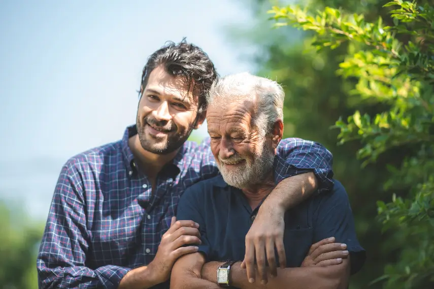 Un père et son fils, d’une quarantaine d’années, souriants et heureux, partagent un moment de complicité.