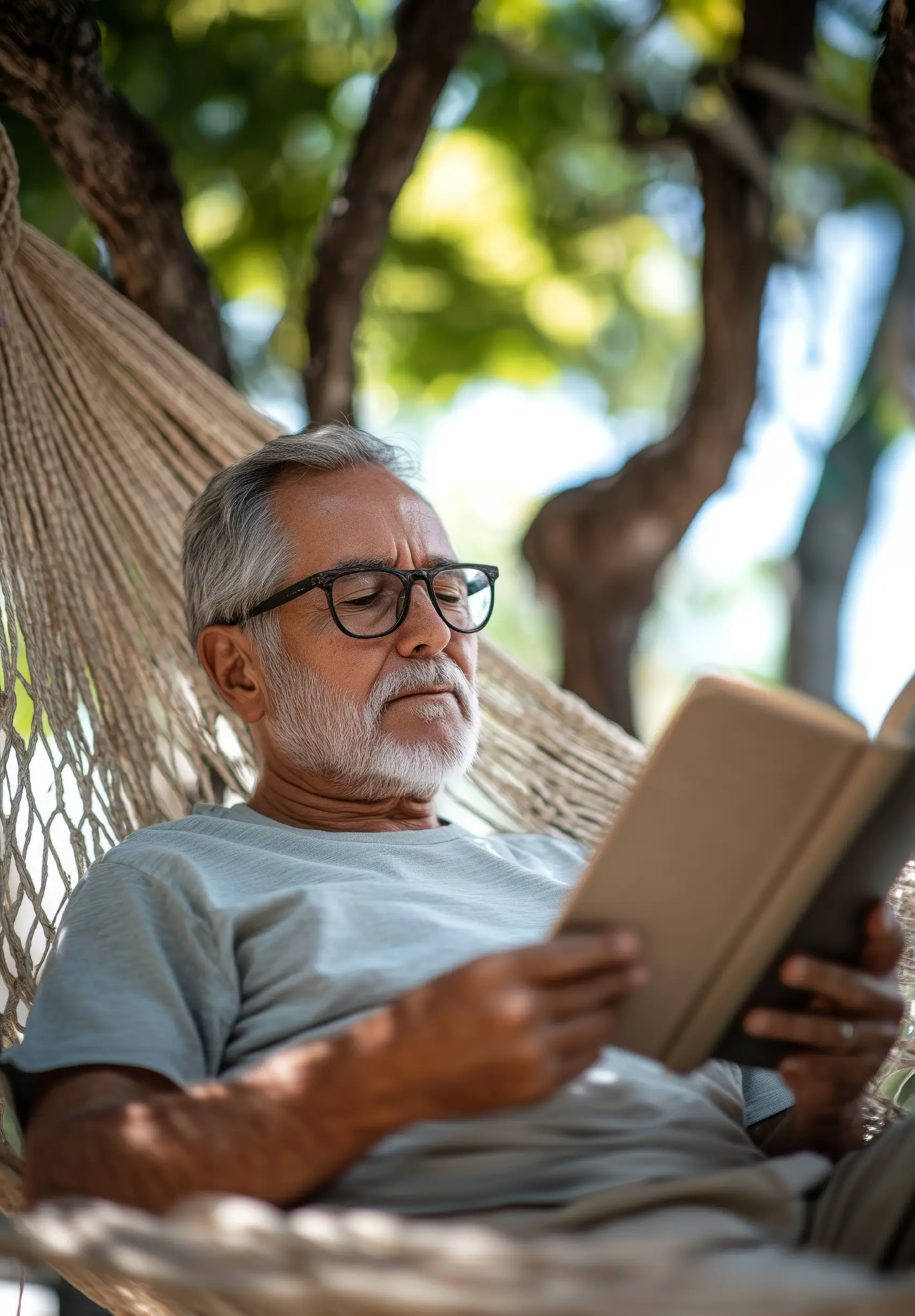 Senior profitant d’un moment de détente en lisant un livre dans son hamac.