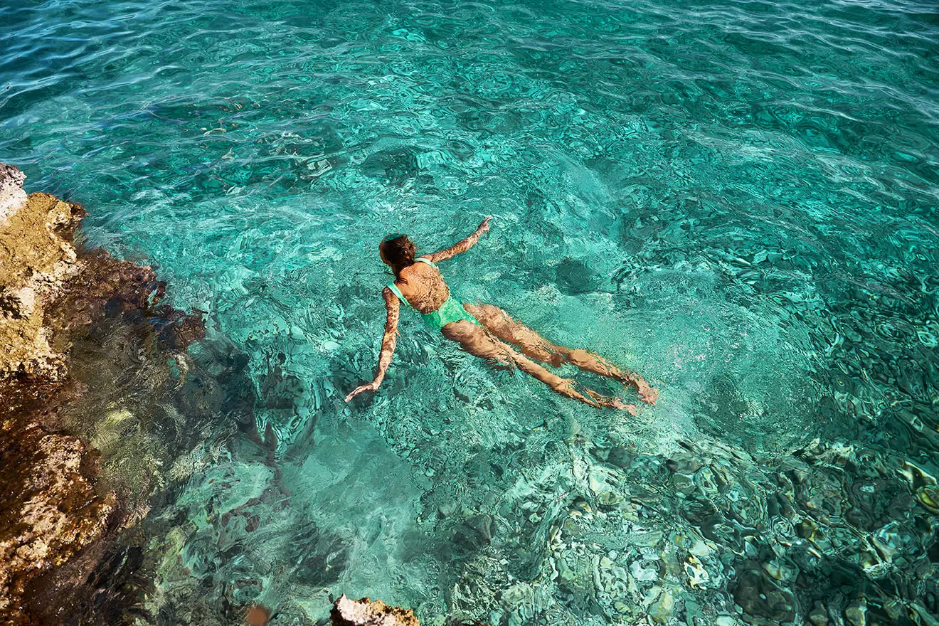 Une jeune femme qui nage dans une eau turquoise.